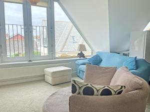 a living room with a blue couch and a large window at 6 Pentire Mews in Newquay