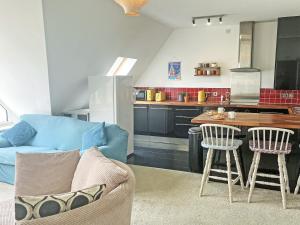 a living room with a blue couch and a kitchen at 6 Pentire Mews in Newquay