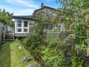 ein Steinhaus mit einem Garten davor in der Unterkunft Primula House in Sticklepath