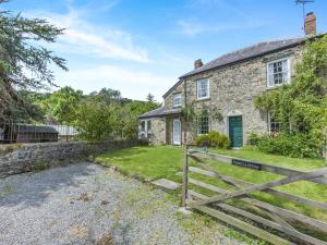 ein altes Steinhaus mit einem Tor davor in der Unterkunft Primula House in Sticklepath
