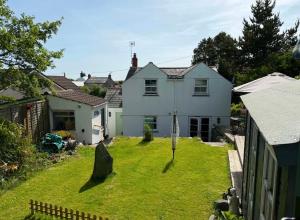 a white house with a lawn in front of it at Shepherds Hut in St Austell
