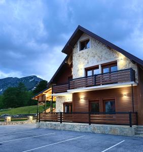 a large building with a balcony and a parking lot at Tri ville in Žabljak