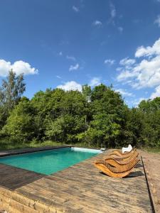 a swimming pool with two chairs on a wooden deck at Agroturystyka Kostomłoty Nad Bugiem in Kodeń