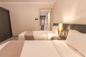 a hotel room with two beds and a lamp at عالم الضيافة in Al ‘Azīzīyah