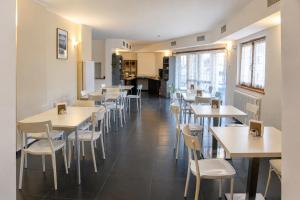a dining room with white tables and chairs at Hotel Radis in Forni di Sotto