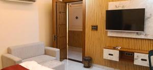 a living room with a chair and a television on a wall at Hotel rajveer in Jhānsi
