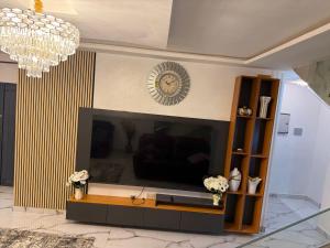 a living room with a large television and a chandelier at Asibbey Lodge in Maijaw