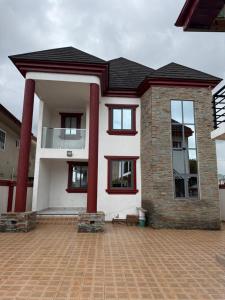 a house with red columns and a brick driveway at Asibbey Lodge in Maijaw