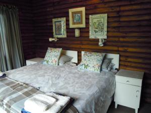 1 dormitorio con 1 cama y algunas fotos en la pared en Forest Drive Holiday Home, en Nature's Valley