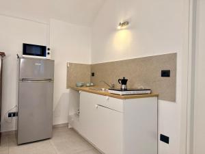 a white kitchen with a sink and a refrigerator at Fuga nel borgo in Avigliana