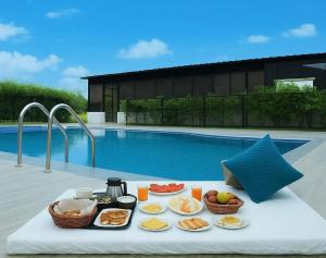 a tray of food on a table next to a pool at Vasant Corbett Resort By Mannat in Rāmnagar