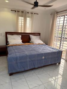 a bed in a bedroom with a blue comforter at Asibbey Lodge in Maijaw