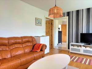 a living room with a brown leather couch and a tv at Villa Dångebo in Tingsryd