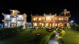 a large building with a yard at night at Vasant Corbett Resort By Mannat in Rāmnagar