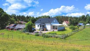 a white house in a field with a fence at Villa Dångebo in Tingsryd