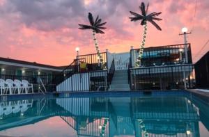 a pool with two palm trees and a building at Surfcomber Motel in Wildwood