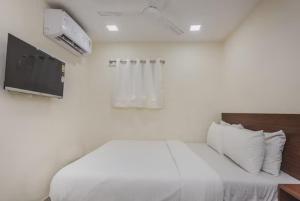 a bedroom with a white bed and a tv at Uma Residency - Chakala in Mumbai