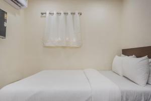 a white bed with white pillows and a window at Uma Residency - Chakala in Mumbai