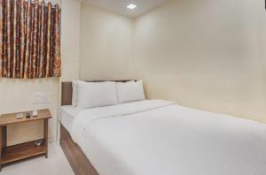 a white bedroom with a white bed and a table at Uma Residency - Chakala in Mumbai