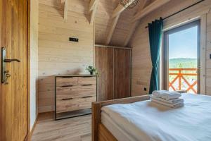 a bedroom with a bed and a large window at Osada Gorczański Zakątek in Nowy Targ