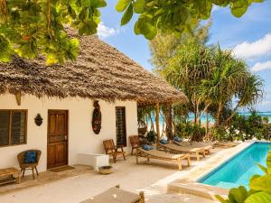 a villa with a swimming pool next to a resort at Poa Poa Bungalows in Kiwengwa