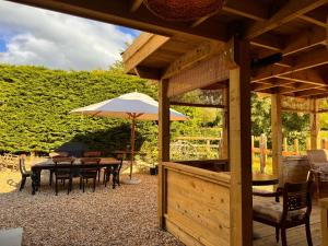 a patio with a table and an umbrella at Dovecote Cotswold Cottages in Chipping Norton