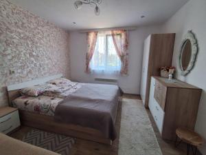 a bedroom with a bed and a dresser and a window at Къща за гости ИЛТА in Novo Delchevo