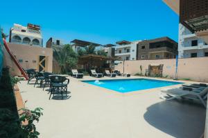 a swimming pool with chairs and a table and a building at Luxor Guest House in Luxor