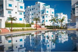a large building with palm trees and a swimming pool at Apartment inside a apartment complex by the beach with public pool in Marina Smir