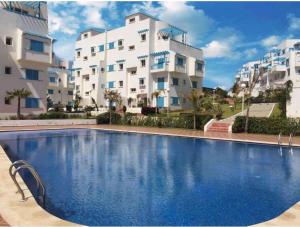 a large swimming pool in front of a building at Apartment inside a apartment complex by the beach with public pool in Marina Smir