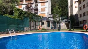 a large blue swimming pool in front of a building at Apartamento Arañones in Canfranc-Estación +5 photos