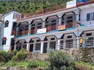 a white building with balconies on top of a hill at Hotel B M AND SONS in Phata