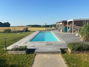 a swimming pool with a wooden deck and a house at B&B Les Autres Sens in Villers-la-Ville