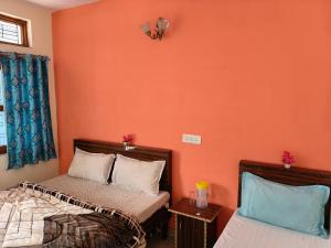a bedroom with two beds and an orange wall at Hotel B M AND SONS in Phata +107 photos