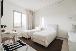 a white bedroom with two beds and a desk at Ritrovare Country House in Citta' Sant'Angelo