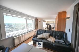 a living room with a leather couch and a large window at Drakkar in Wenduine