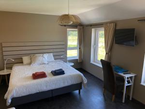 a bedroom with a bed and a chair and windows at B&B Les Autres Sens in Villers-la-Ville