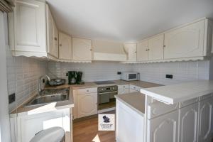 a white kitchen with white cabinets and a sink at Drakkar in Wenduine +13 photos