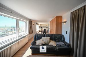 a black leather couch in a room with a large window at Drakkar in Wenduine