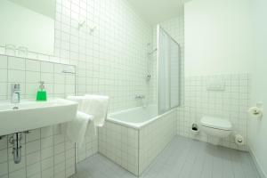 a white bathroom with a sink and a tub and a toilet at Flair Hotel Reuner in Zossen