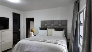 a bedroom with a large white bed and a flat screen tv at Lora Gardens in Chartwell