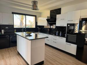 a kitchen with white cabinets and a black counter top at Prestige Pool Retreat in Hammamet