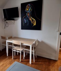 a table and chairs in a room with a painting on the wall at Appartement T2 Proche du CH d'Arras in Sainte-Catherine