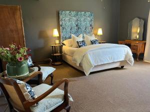 a bedroom with a large bed and a chair at Kamieskroon Hotel in Kamieskroon