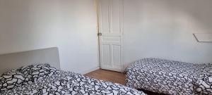 a bedroom with two beds and a door to a room at Appartement T2 Proche du CH d'Arras in Sainte-Catherine