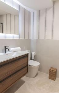a bathroom with a toilet and a sink and a mirror at Apartamentos Turísticos A Mariña Do Carril in Vilagarcia de Arousa +30 photos