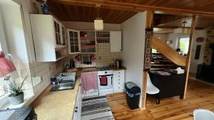 a small kitchen with white cabinets and a staircase at Malinowa Chatka Mostki in Mostki