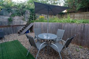 a table and chairs with an umbrella in a garden at Modern 3 Bed Flat - 3 En-Suites - Parking - near Wembley in Edgware