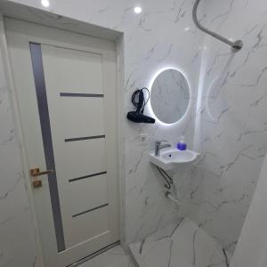 a white bathroom with a sink and a mirror at Byrabau Tauwer in Shchūchīnsk