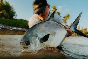 a man holding a fish in the water at Tranquility Bay Resort in San Pedro